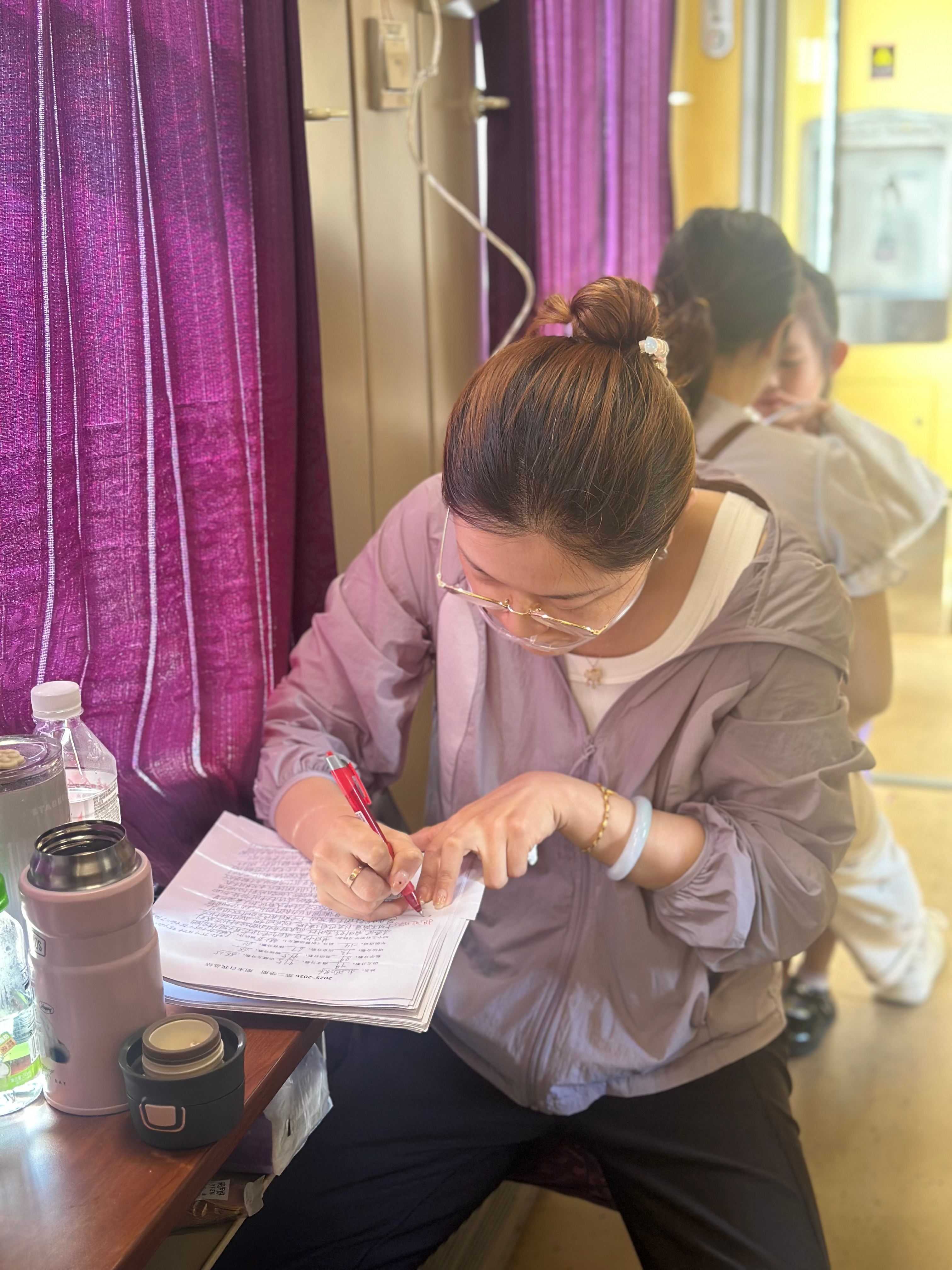 吉婷老师在前往拉萨的列车上边吸氧边批改学生总结。